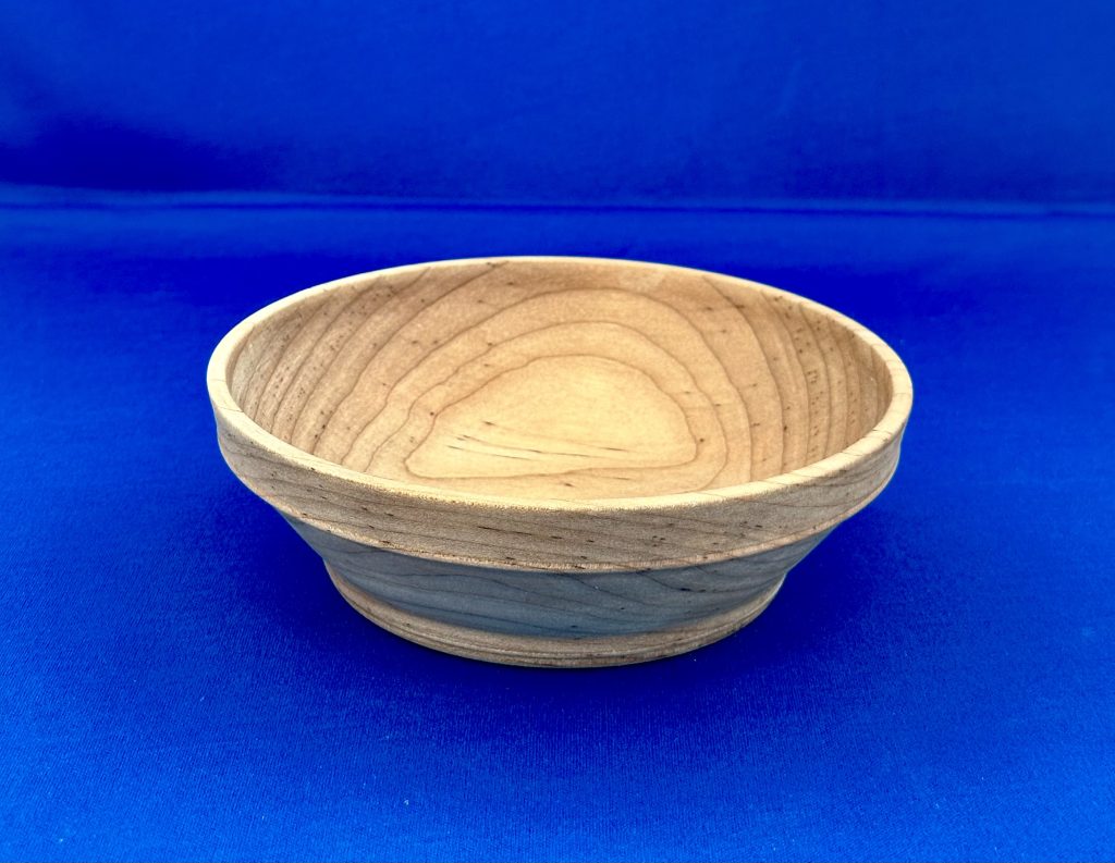 Shallow handcrafted wooden bowl with flowing grain