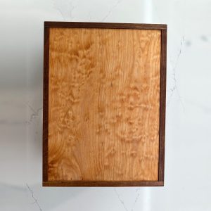Top view of the bookmatched birdseye maple lid framed in dark walnut