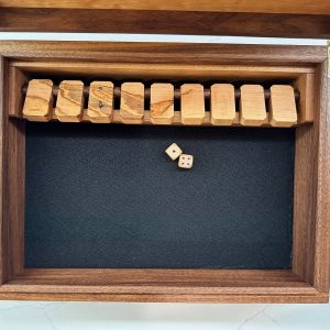 Top-down view of the Shut the Box playing area with flipped wooden tiles and dice