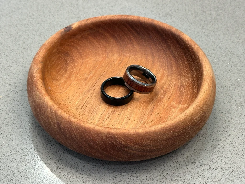 Two rings resting inside a shallow wooden dish on a countertop.