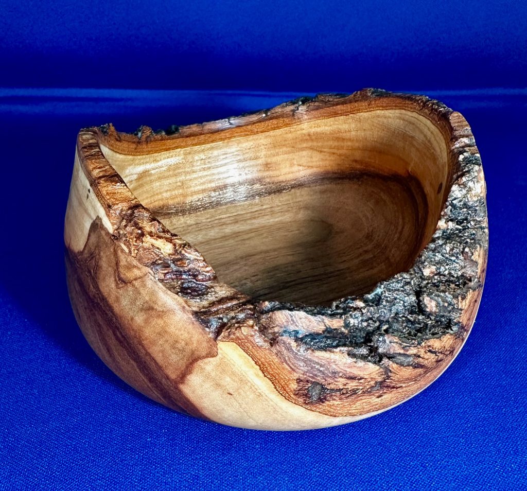Alternate view of a live-edge cherry bowl showing its natural bark and flowing grain