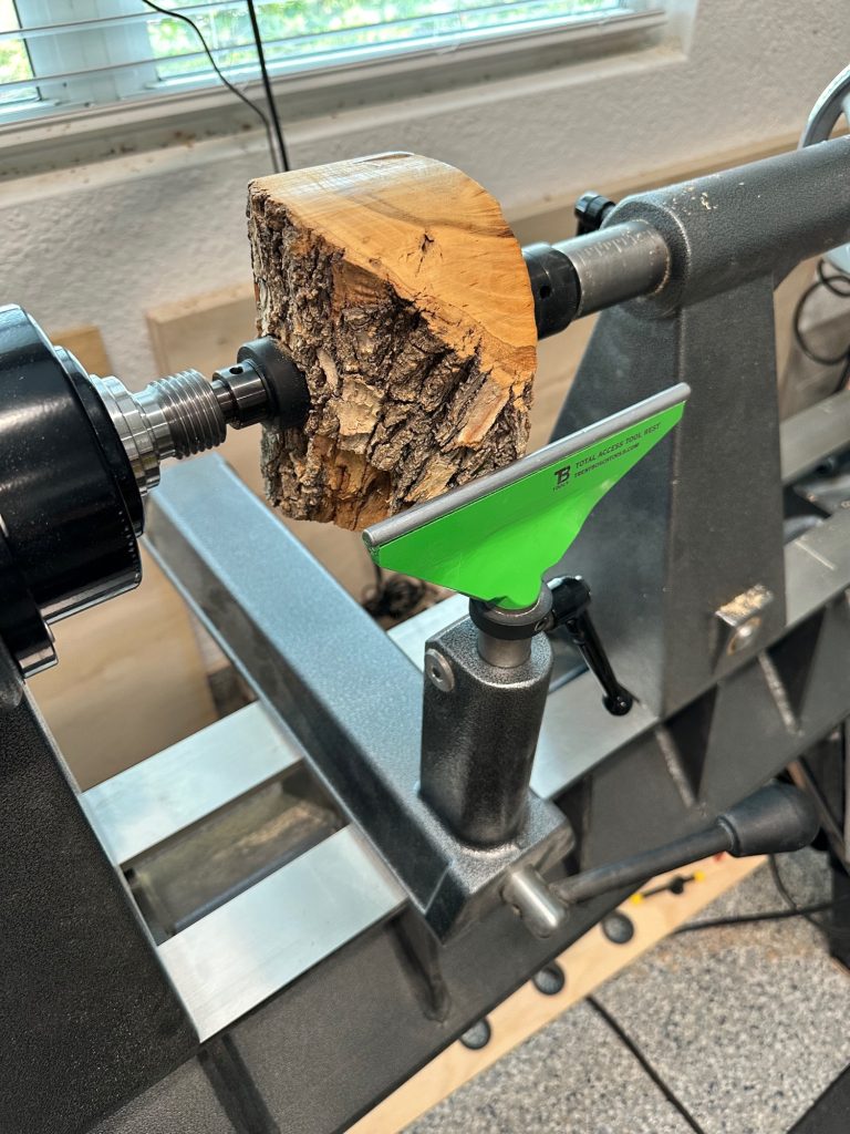 Rough live-edge cherry blank mounted on a wood lathe before turning