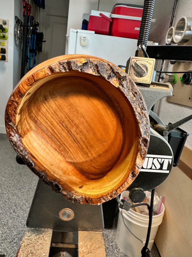 Live-edge cherry bowl on a lathe with its freshly turned interior exposed