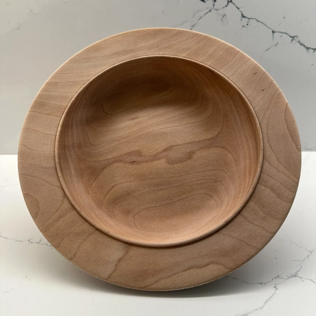 Angled view of a shallow sycamore bowl with a broad rim and flowing grain across its interior.