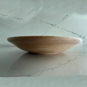 Side view of a shallow sycamore bowl with a gently curved body and a small raised foot.