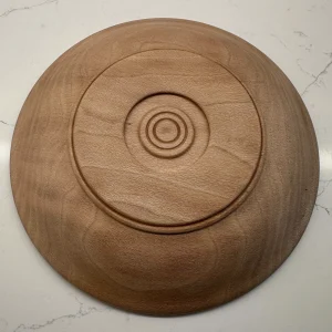 Underside of a sycamore bowl showing a circular foot and decorative concentric rings at the center.