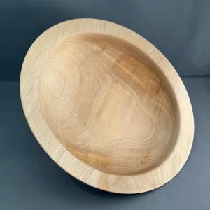 Angled view of a shallow sycamore wood bowl with a thin rim and distinctive end-grain patterns.